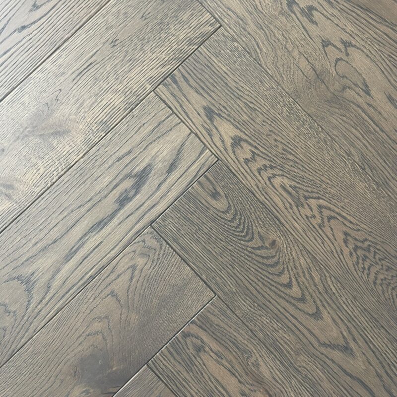 Antique Grey Engineered Oak Herringbone flooring featuring a timeless, elegant pattern with a soft, muted grey tone and natural oak grain texture. The interlocking herringbone design creates a sophisticated and classic look, perfect for enhancing any interior space