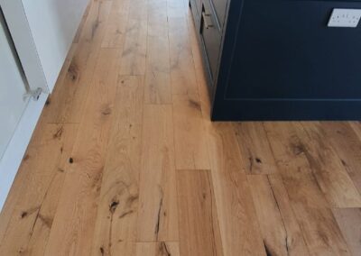 Medium oak engineered wood flooring in a modern kitchen with natural grain and character knots.