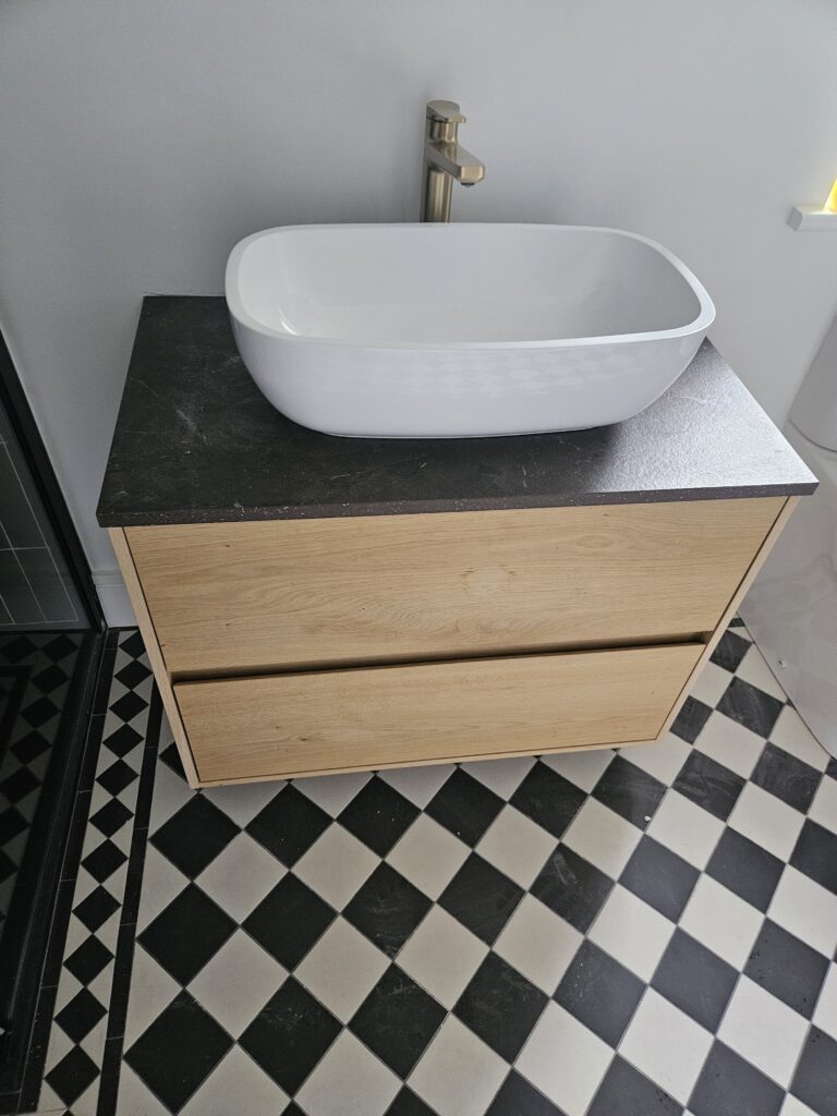 Grain & Groove bespoke wooden vanity unit with countertop basin, paired with Victorian black-and-white checker floor tiles.